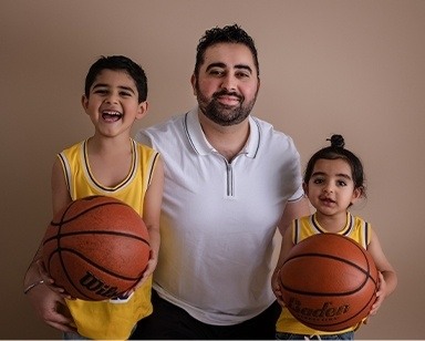 Doctor Navi Dhaliwal's husband with their two sons wearing basketball uniforms