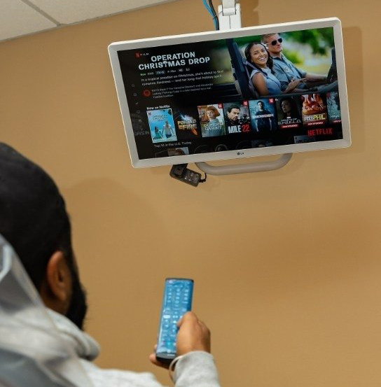 Dental patient using remote on wall mounted television in Federal Way dental office