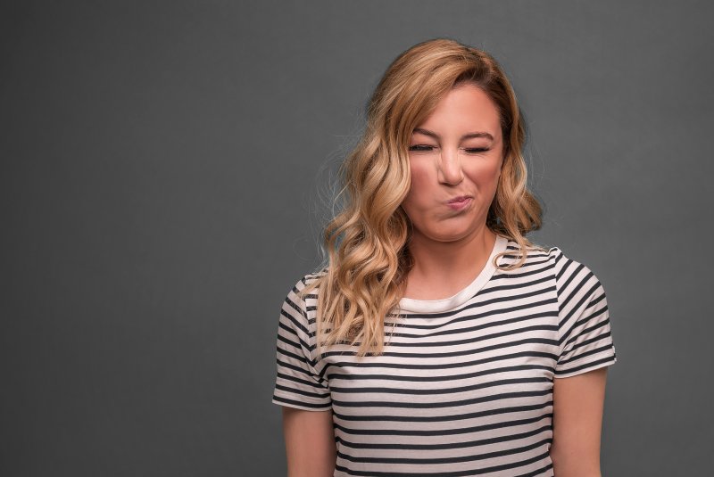 Patient wincing from a bitter taste that may be a dental emergency